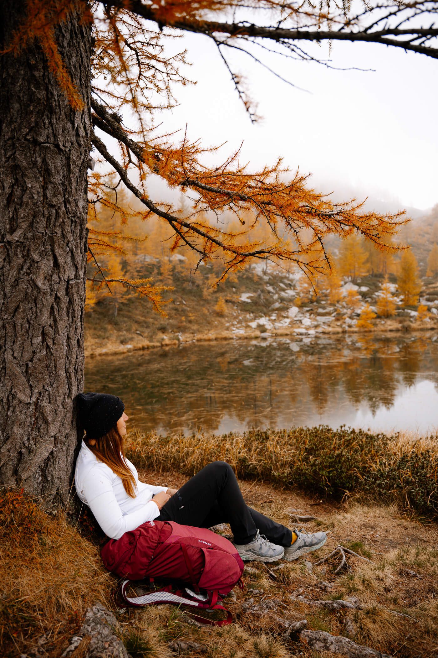 Person sitzt am Baum am See